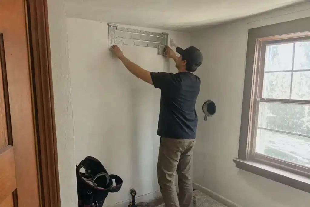 Cool Ducts HVAC technician mounting the wall bracket for a ductless mini split indoor unit during an installation in a Greeley home
