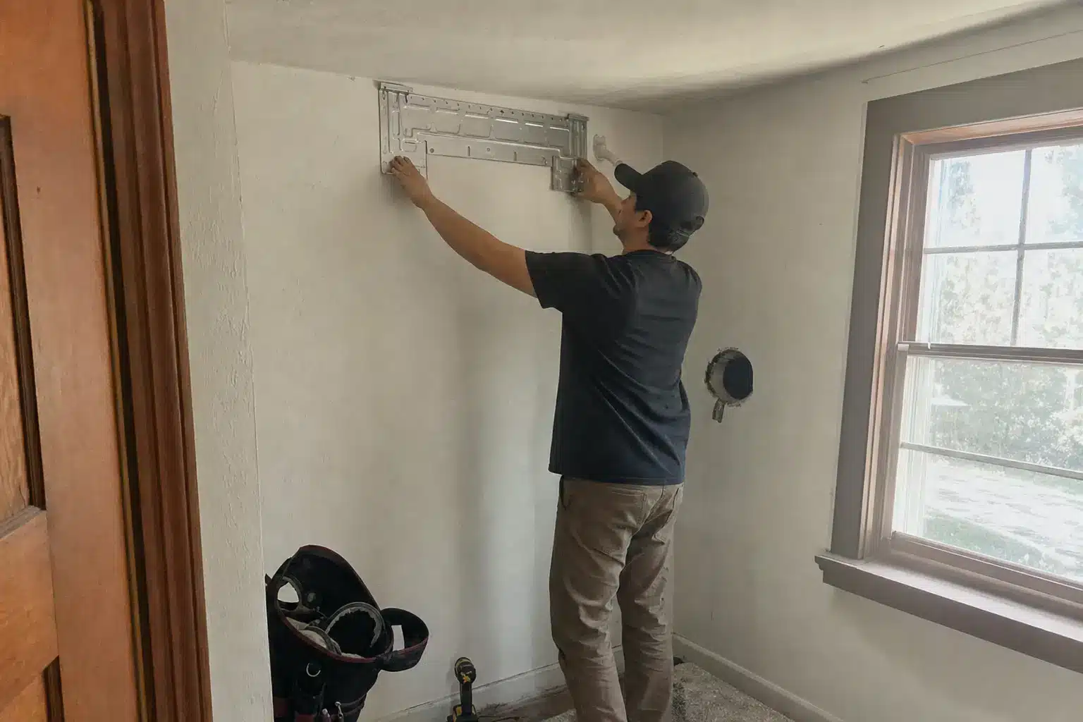 Cool Ducts HVAC technician mounting the wall bracket for a ductless mini split indoor unit during an installation in a Greeley home